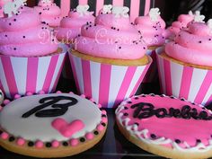 cupcakes decorated with pink frosting and black icing are sitting on a table