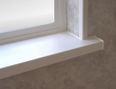 a window sill in a bathroom next to a tiled wall