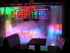 a restaurant with neon lights on the walls and tables in front of an open window