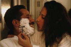 a man shaving a woman's face with a razor in front of him