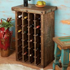 a wooden wine rack sitting next to a table with a vase and fruit on it