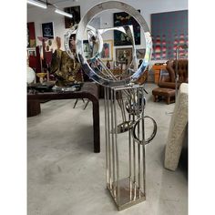 a metal sculpture with circular mirrors on it's sides in a room filled with furniture