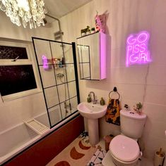 a bathroom with a pink neon sign on the wall above the toilet and sink area