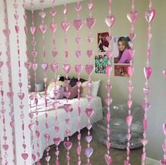 a bedroom decorated with pink hearts hanging from the ceiling and pictures on the wall above it