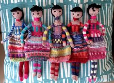 three knitted dolls sitting on top of a pillow