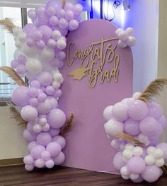 balloons and streamers are on display in front of a purple sign that says congratulations