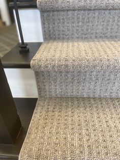 a carpeted stair case sitting on top of a wooden floor next to a metal hand rail