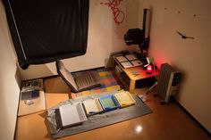 a room with a desk, chair and books on the floor next to a heater