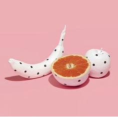 an orange cut in half sitting on top of a pink surface with polka dot print