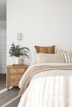 a bedroom with white walls and neutral bedding