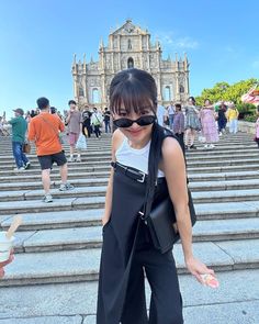 a woman in black pants and sunglasses standing on steps