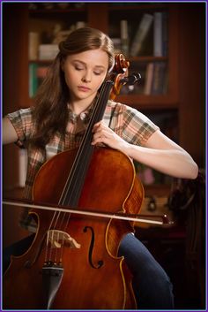 a woman sitting in front of a cello