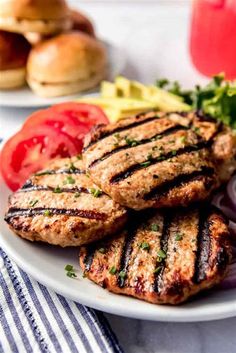 grilled chicken patties on a white plate with tomatoes and lettuce