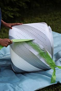 a person cutting paper on top of a piece of cloth in the grass with scissors