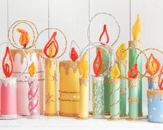 several colorful candles are lined up on a white surface with gold and red decorations around them