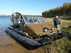 a man standing next to a boat in the water with a machine on it's back