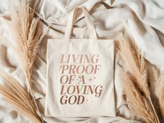 "Living Proof of a Loving God Drop the perfect gift for a Christian friend's birthday or special occasion! Wear to casual events or everyday work situations. This 100% cotton bag comes in one size - 15\" x 16\"- perfect for everyday wear. The bag features 20\" handles (made from the same canvas), making it easy to carry even with a week's worth of shopping. 🔸 100% cotton canvas 🔸 Natural Color 🔸 Heavy fabric (12 oz/yd² (406.9 g/m 🔸 Sewn-in label Got questions? Send us a message! ❣️Enjoy our other designs perfect for gifting all year round! https://www.etsy.com/shop/AWJPrints Christian Girl Tote Bag, Christian Gift for Her, Christian Gift Idea, Teacher Tote Bag, Nurse Work Tote Bag, Colorful Canvas Everyday Bag" Inspirational Bags For Mother's Day Gift, Inspirational Bags For Daily Use And Mother's Day, Rectangular Canvas Bag With Letter Print For Gift, Mother's Day Gift Shoulder Bag With Letter Print, Pink Canvas Gift Bag, Christian Bags, Painted Tote Bag Ideas Christian, Christian Tote Bag Design, Tote Bag Christian