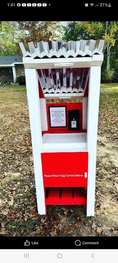 a red and white cabinet sitting in the middle of a field with leaves on the ground