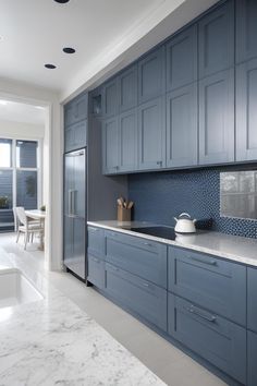 a kitchen with blue cabinets and marble counter tops, along with a white dining room table