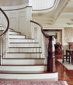 a staircase leading up to a dining room and living room in an old style home