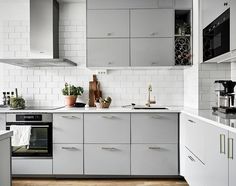 a kitchen with gray cabinets and white subway backsplashes is pictured in this image