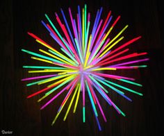 colorful sticks are arranged in the shape of a star on a dark surface with lightening effect