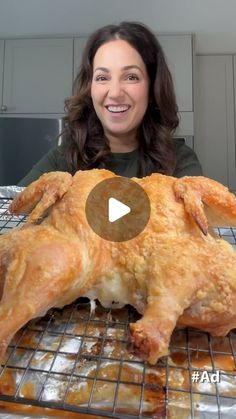 a woman sitting in front of a chicken on top of a metal rack with gravy