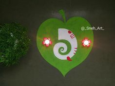 a green heart shaped sign with candles on it next to a potted plant in the shape of a 6