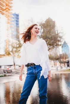 a woman in white shirt and jeans walking on wet ground