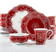 a red and white dinnerware set with snowflakes on the plates, cups and saucers