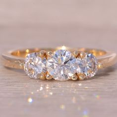 three stone diamond ring sitting on top of a wooden table