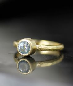 two gold rings with a blue topazte stone on the middle one and a black background