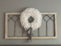 a wreath is hung on the wall above a window frame with a ribbon tied around it