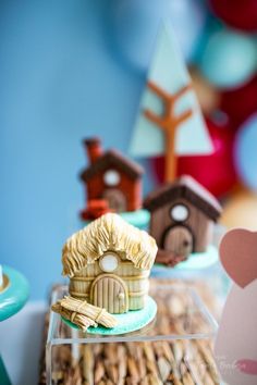 some little houses are on display in front of balloons and other decorations for a birthday party