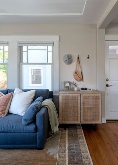 a living room with a blue couch and wooden flooring next to a white door