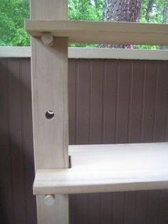 a wooden shelf sitting on top of a window sill next to a tree in the woods