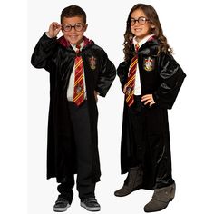 two children dressed in harry potter robes and holding their hands up to their ears while standing next to each other