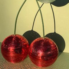 two shiny red disco balls sitting next to each other on top of a countertop