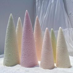 five different colored cones sitting on top of a white tablecloth covered surface with a curtain in the background