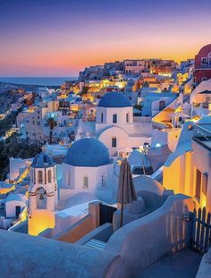 the sun is setting over some white buildings with blue domes on them in oia, greece