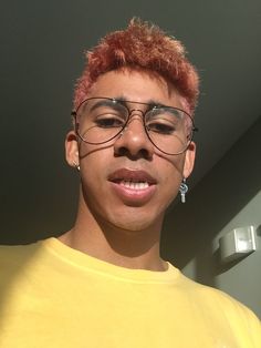 a man with red hair and glasses is smiling at the camera while wearing a yellow t - shirt