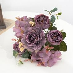 a bouquet of purple flowers sitting on top of a white table