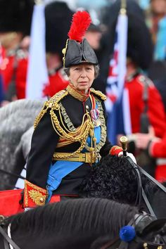 a woman riding on the back of a horse wearing a black hat and red plumes