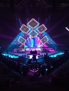 the stage is lit up with purple and blue lights, while people are standing on it