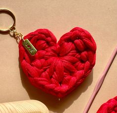 a red heart shaped keychain sitting on top of a table next to a pair of scissors