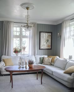 a living room filled with furniture and a chandelier hanging from the ceiling next to a window