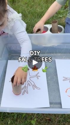 two children playing with paper and scissors on the grass, while one child is drawing