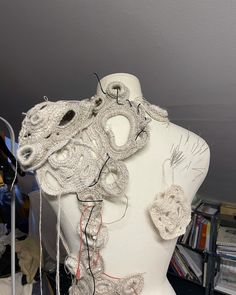 a white mannequin is covered in crochet and yarn with wires attached to it