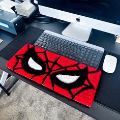 a computer desk with a spiderman rug on it and a keyboard next to it