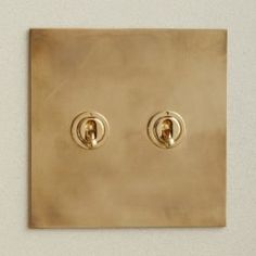 two golden lights are on the wall in front of an electrical outlet with one light switch